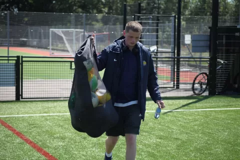 Coach carrying bag of balls